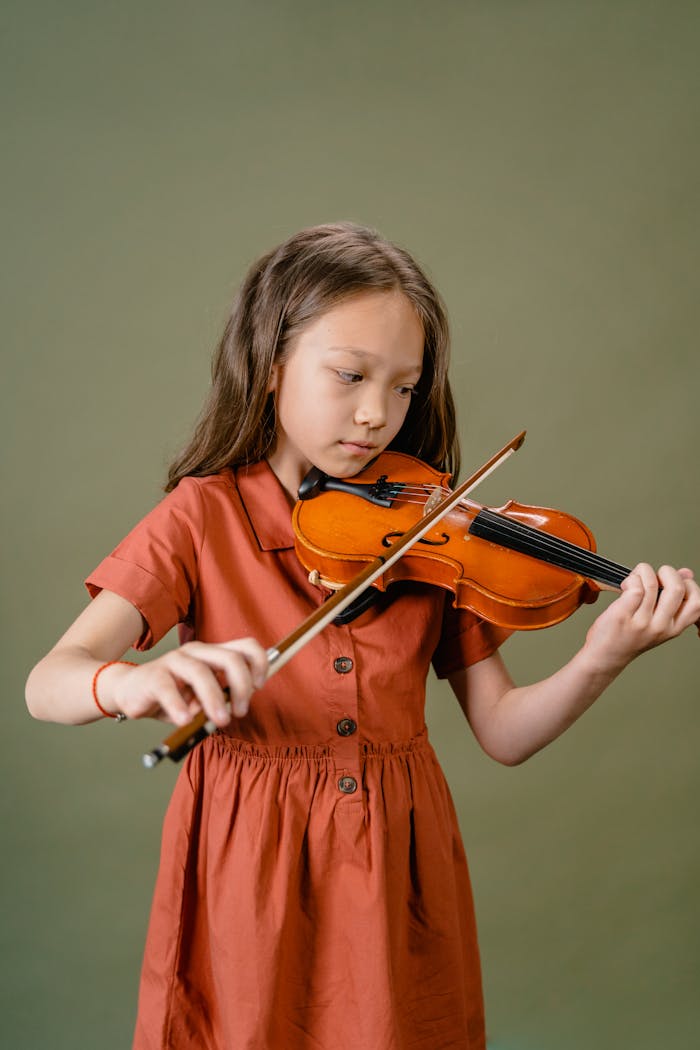 A child focuses intently while playing a violin, showcasing passion for music.