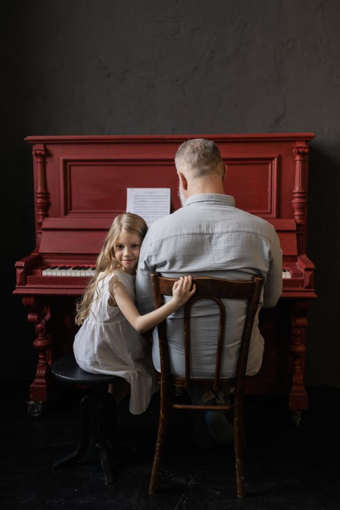 A senior man and young girl playing piano together, fostering musical bonding.
