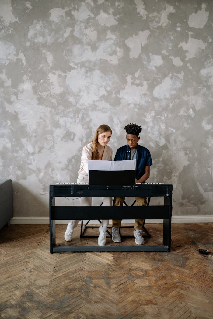 A young boy receives a piano lesson at home from a female instructor, focused and engaged.