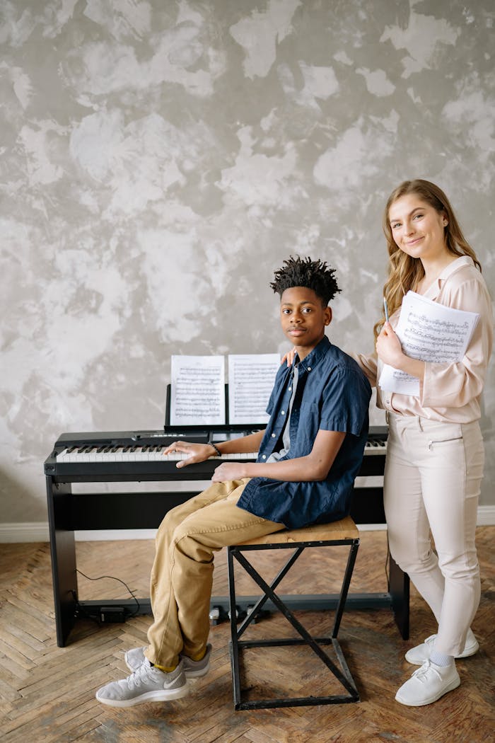 A young musician practices piano with an instructor in a bright indoor setting.